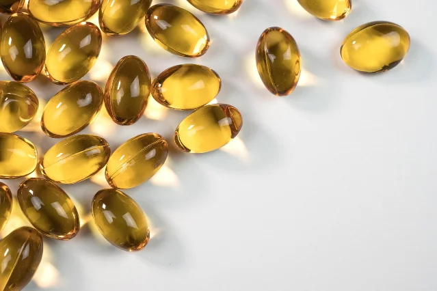 Amber-colored softgel capsules scattered on a white surface