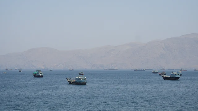 霍尔木兹海峡海域大量商船抛锚等待通航,背景为干旱山地