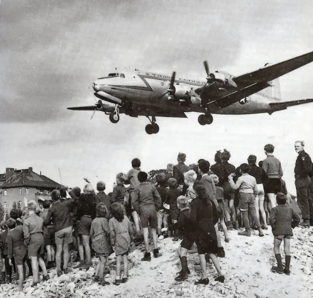 Berliners watch a Douglas C-54 Skymaster descend on approach to Tempelhof Airport, 1948 — Operation Vittles