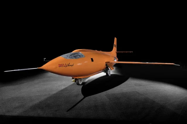 Bell X-1 in international orange livery, side view against dark studio background