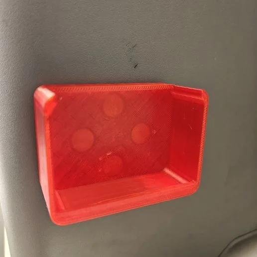 Red MagDock shallow tray mounted on a grey ferrous wall, showing the magnetic adhesion with no visible hardware