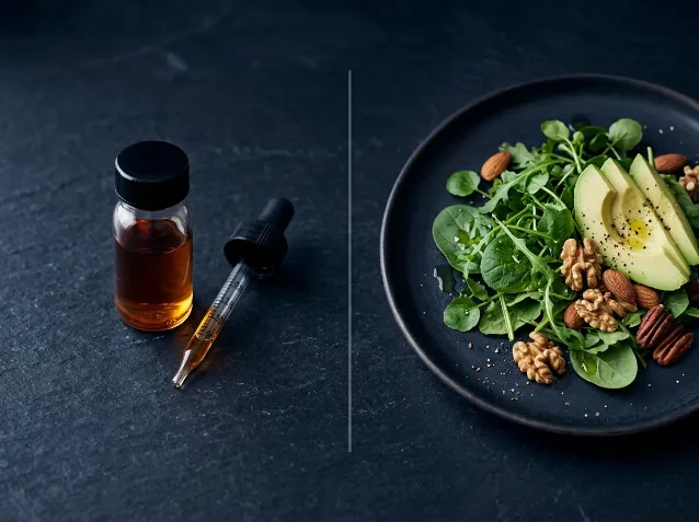 Side-by-side still life: an amber ketone ester supplement vial with dropper on the left, and a plate of avocado, greens, and nuts representing a low-carbohydrate dietary pattern on the right, separated by a dividing line