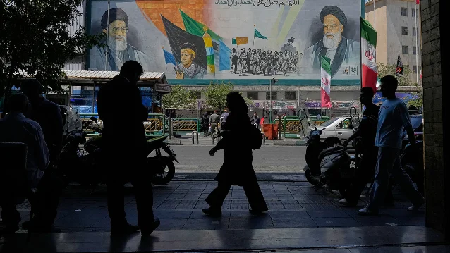 Tehran street, silhouettes against Khamenei-Khomeini mural