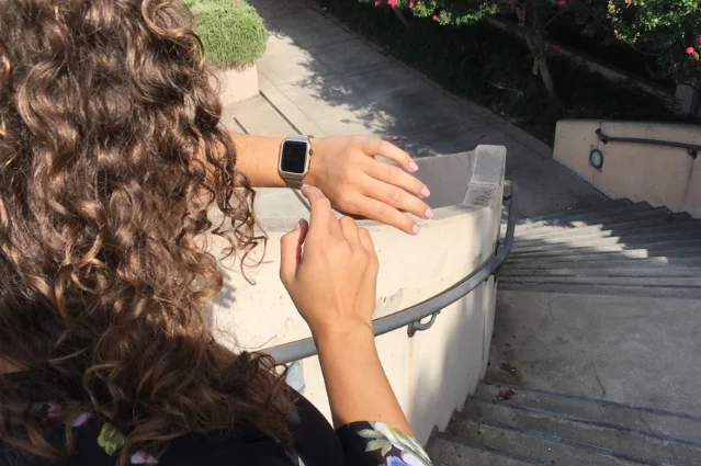 Person checking a smartwatch fitness tracker on their wrist at the top of a staircase
