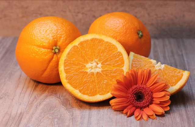 Halved navel oranges on a wooden surface, showing the white pith layer on the cut face