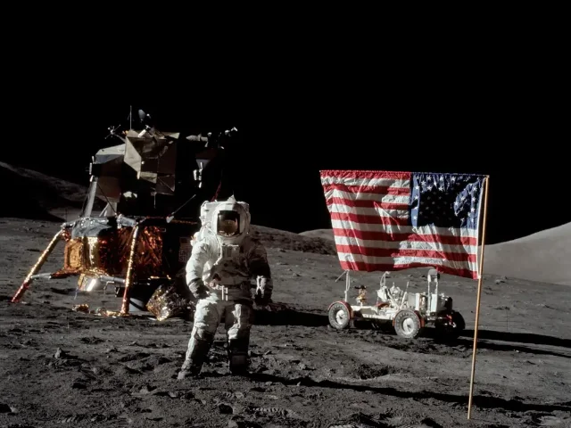 Apollo 17 astronauts on the lunar surface with the American flag, Lunar Module, and rover visible