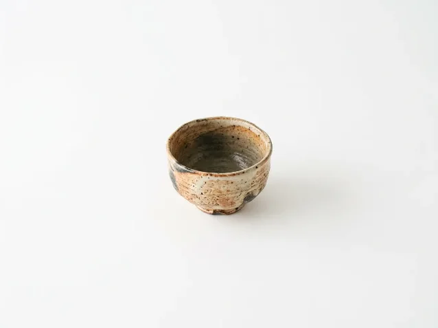 A single Japanese ceramic tea bowl centered on a pure white background with vast empty space surrounding it — negative space composition example