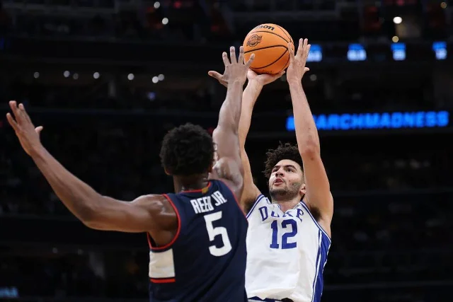 Cameron Boozer (#12, Duke) shoots over Tarris Reed Jr. during the NCAA Tournament with March Madness signage in the background