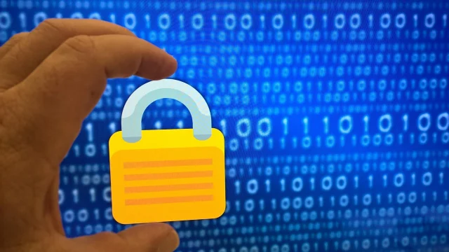 Hand holding a padlock in front of binary code