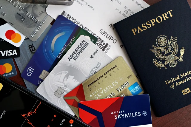 Travel essentials flat lay — passport, credit cards, and a boarding pass on a dark surface, representing the Delta gift card and travel offer stack