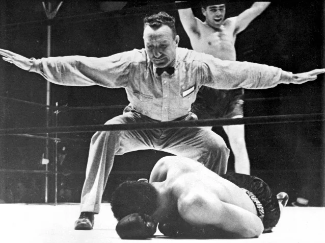 Joe Louis on the canvas, referee Arthur Donovan spreading his arms to signal the fight's end, Schmeling visible in the background with arms raised