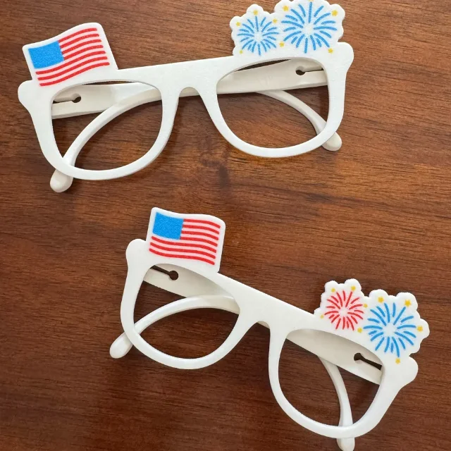 Two finished red, white, and blue July 4 party glasses on a wooden table